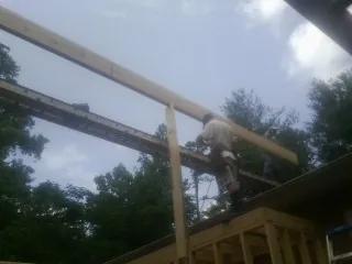 Carpenter setting a ridge beam over a new addition frame — Ice Dam Removal by Roofing Brothers in Furlong