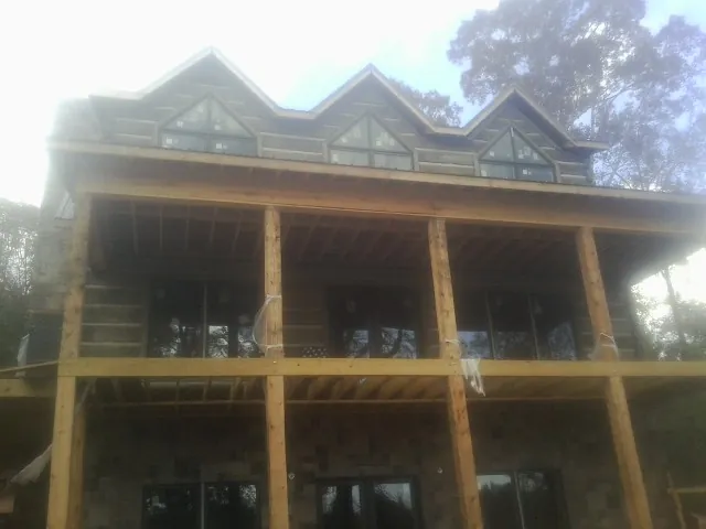 Dormers and porch framing on a large log home under construction — Roof Coating work by our crew in Furlong