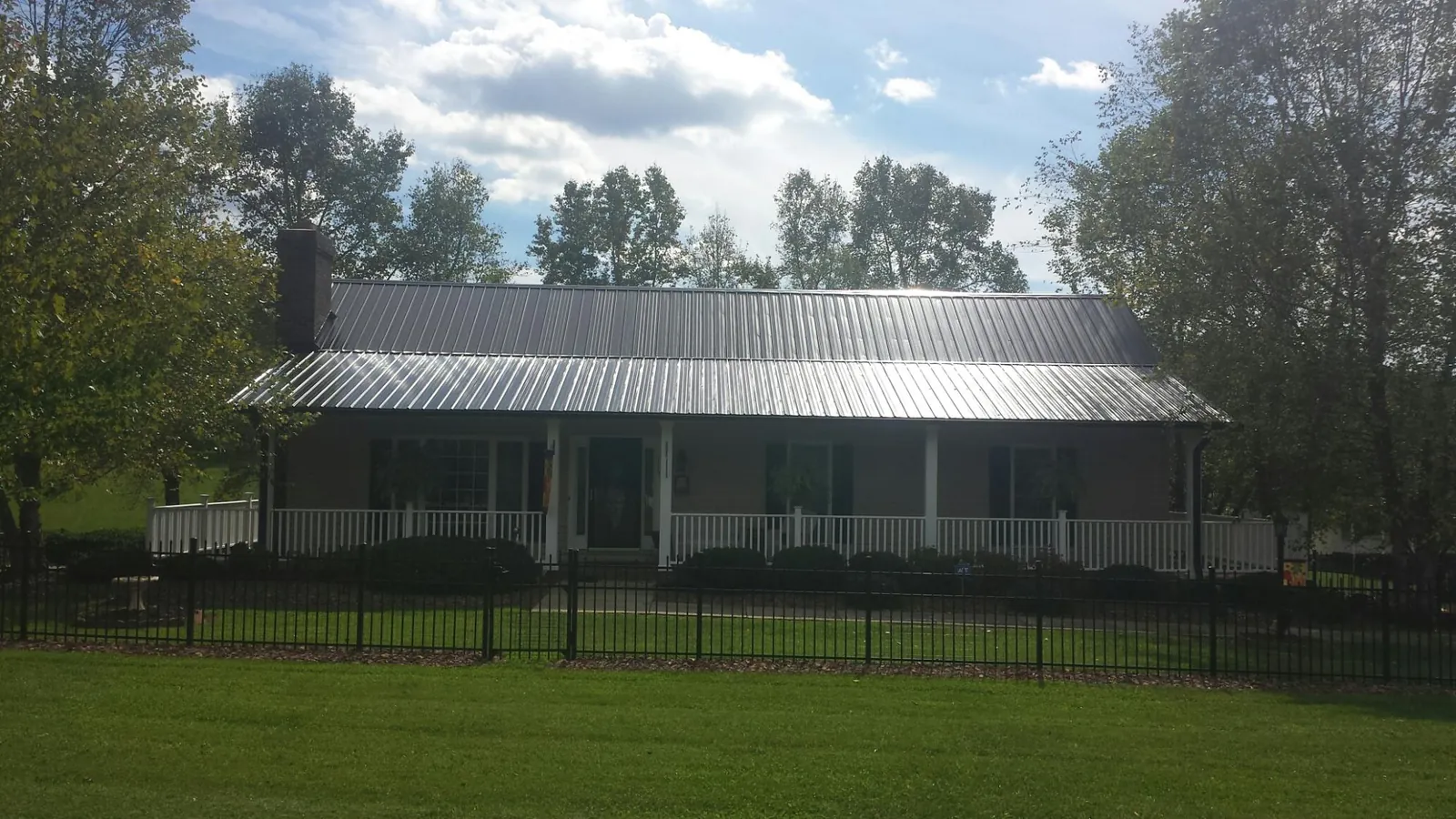 Gray metal roof on a brick ranch with a full width front porch — Gutter Guard Installation work by our crew in Furlong