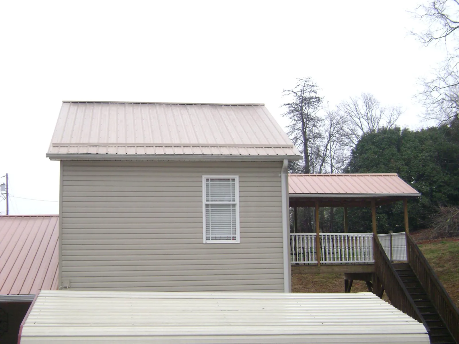 Tan metal roofs on a two story addition and attached porch, from a Roof Replacement job in Furlong