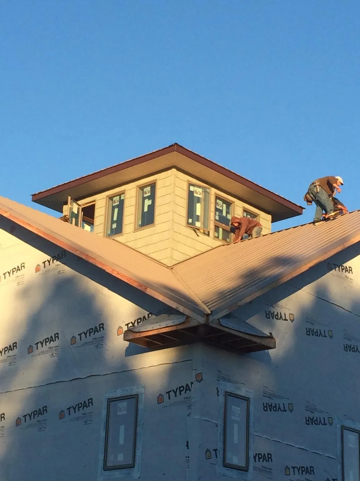 Roofers working around a rooftop cupola on a new metal roof at sunset — Roof Waterproofing in Furlong by Roofing Brothers
